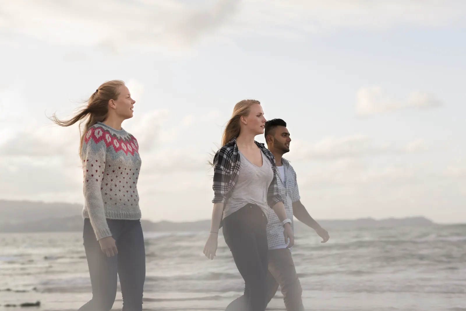 Three students walking along a New Zealand beach